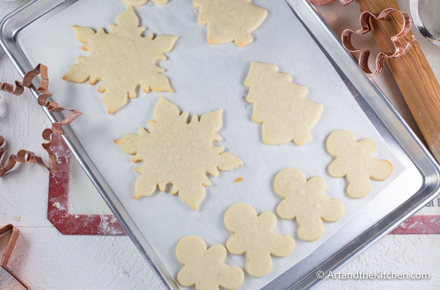 White parchment line baking pan filled with holiday shaped baked cookies.