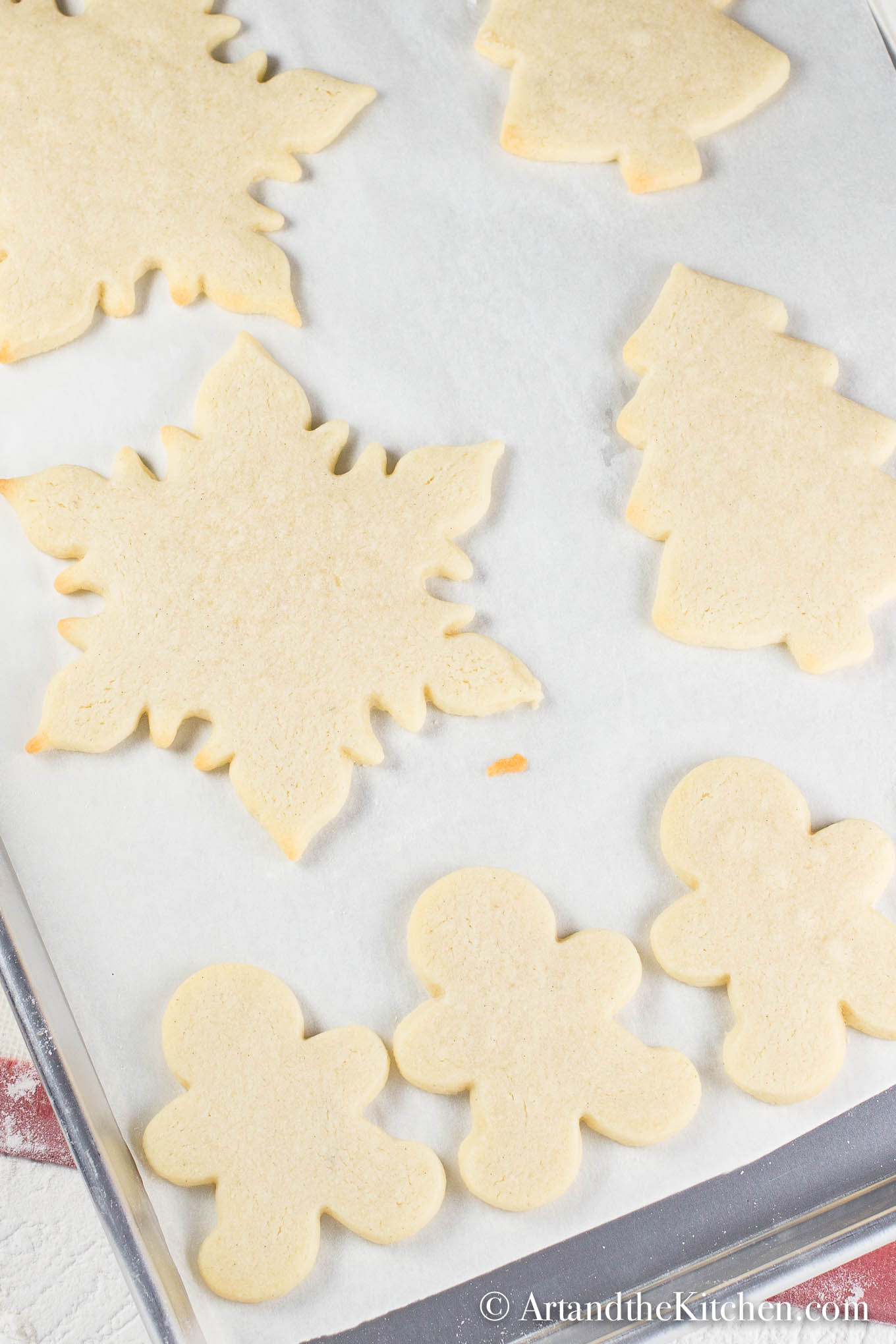 White parchment line baking pan filled with holiday shaped baked cookies.