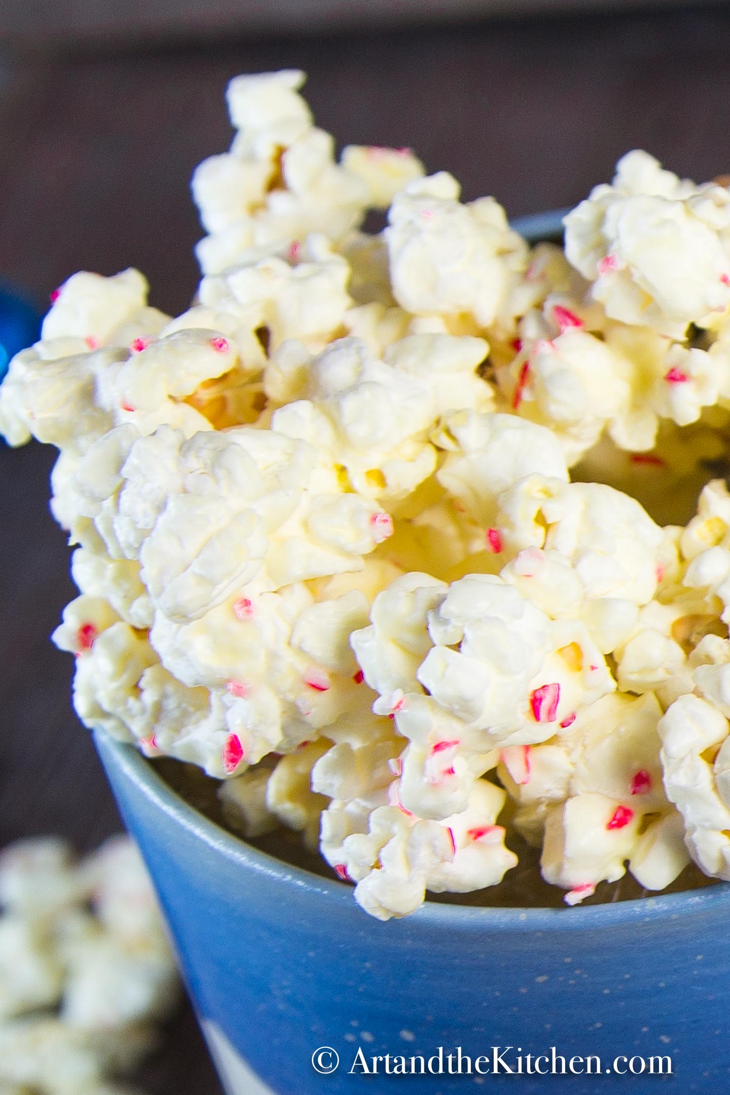 Decorative Holiday container filled with popcorn coated in white chocolate and pieces of candy cane.