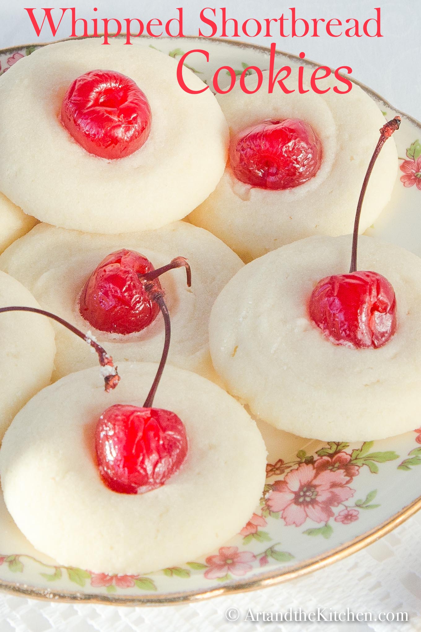 Decorative plate filled with shortbread cookies topped with maraschino cherries.
