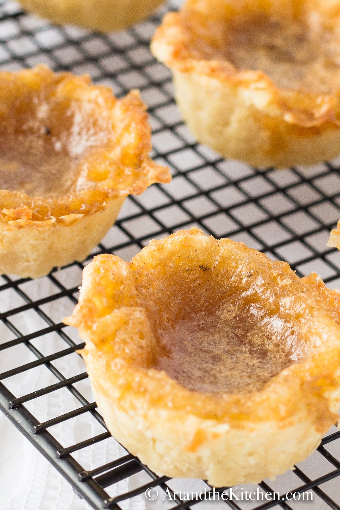 Butter tarts with flaky crust cooling on black wire rack.