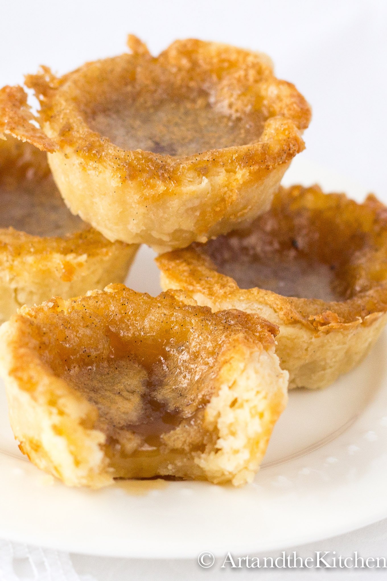 Stack of 4 homemade butter tarts on a white plate.