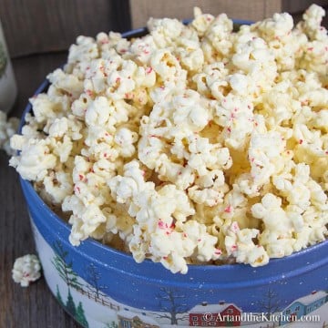 Decorative Holiday container filled with popcorn coated in white chocolate and bits of candy cane.