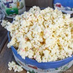 Decorative Holiday container filled with popcorn coated in white chocolate and pieces of candy cane.