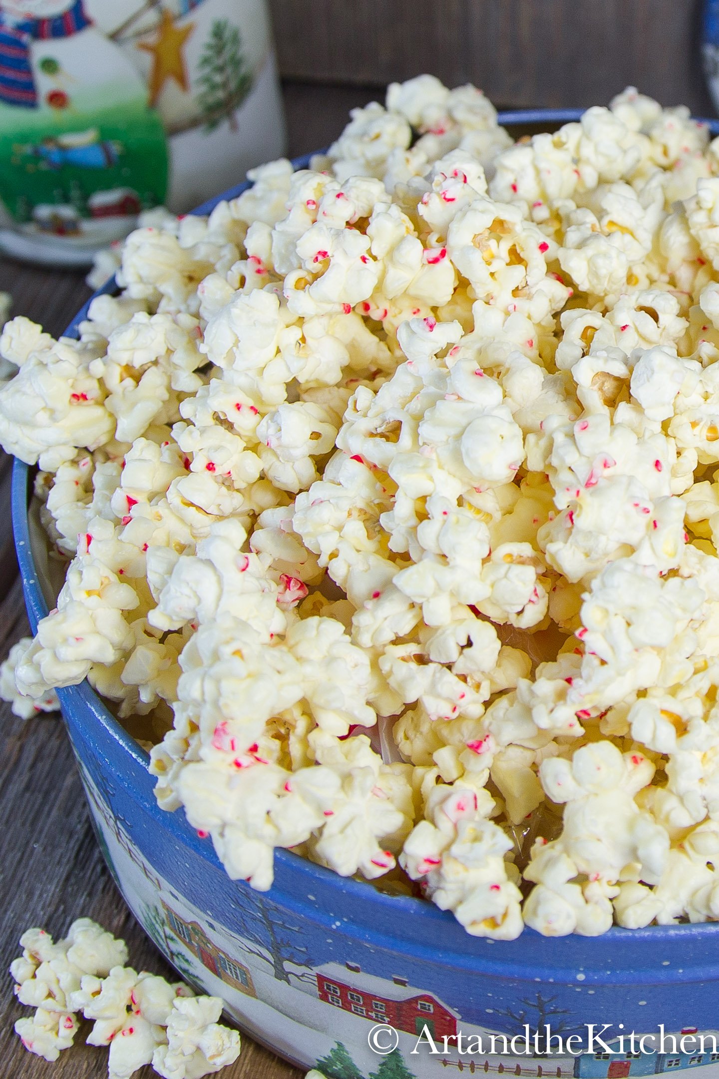 Decorative Holiday container filled with popcorn coated in white chocolate and pieces of candy cane.