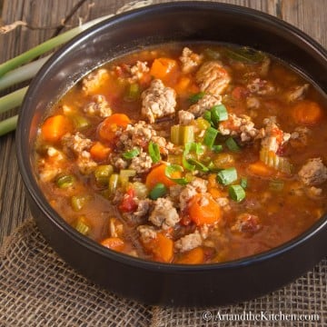 Soup with chunks of ground turkey, vegetables simmered in a tomato beef broth served in a black bowl