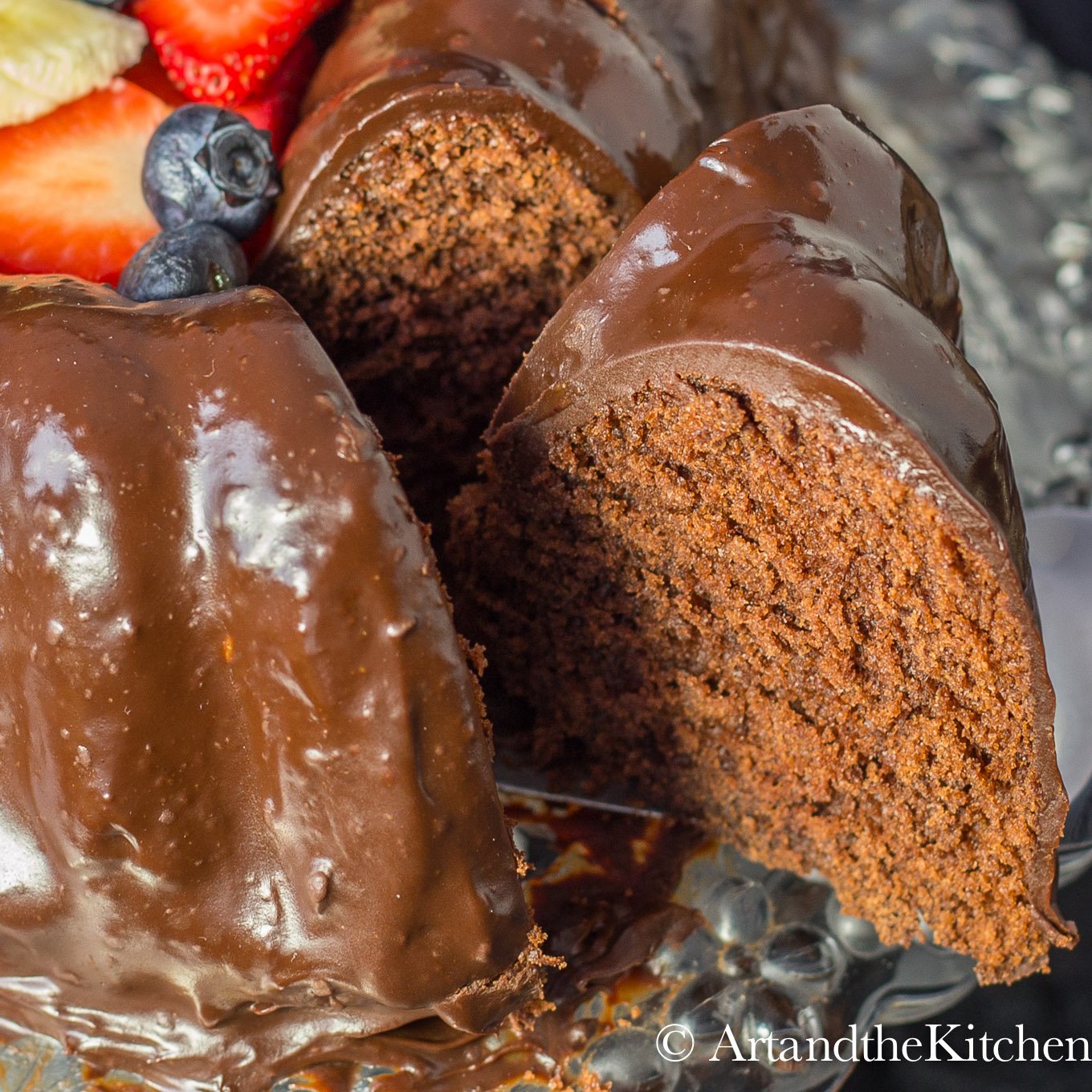 Chocolate cake with slice taken out from cake. Covered in chocolate ganache.