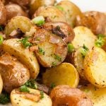 Roasted baby potatoes with crispy skins, garnished with chopped green onions and parsley.