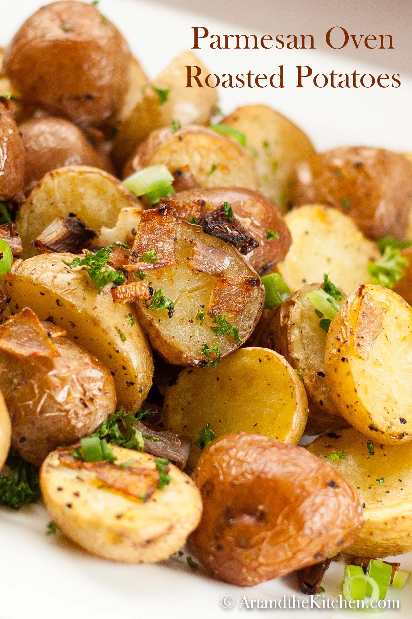 Plate of golden roasted potatoes garnished with green onions.