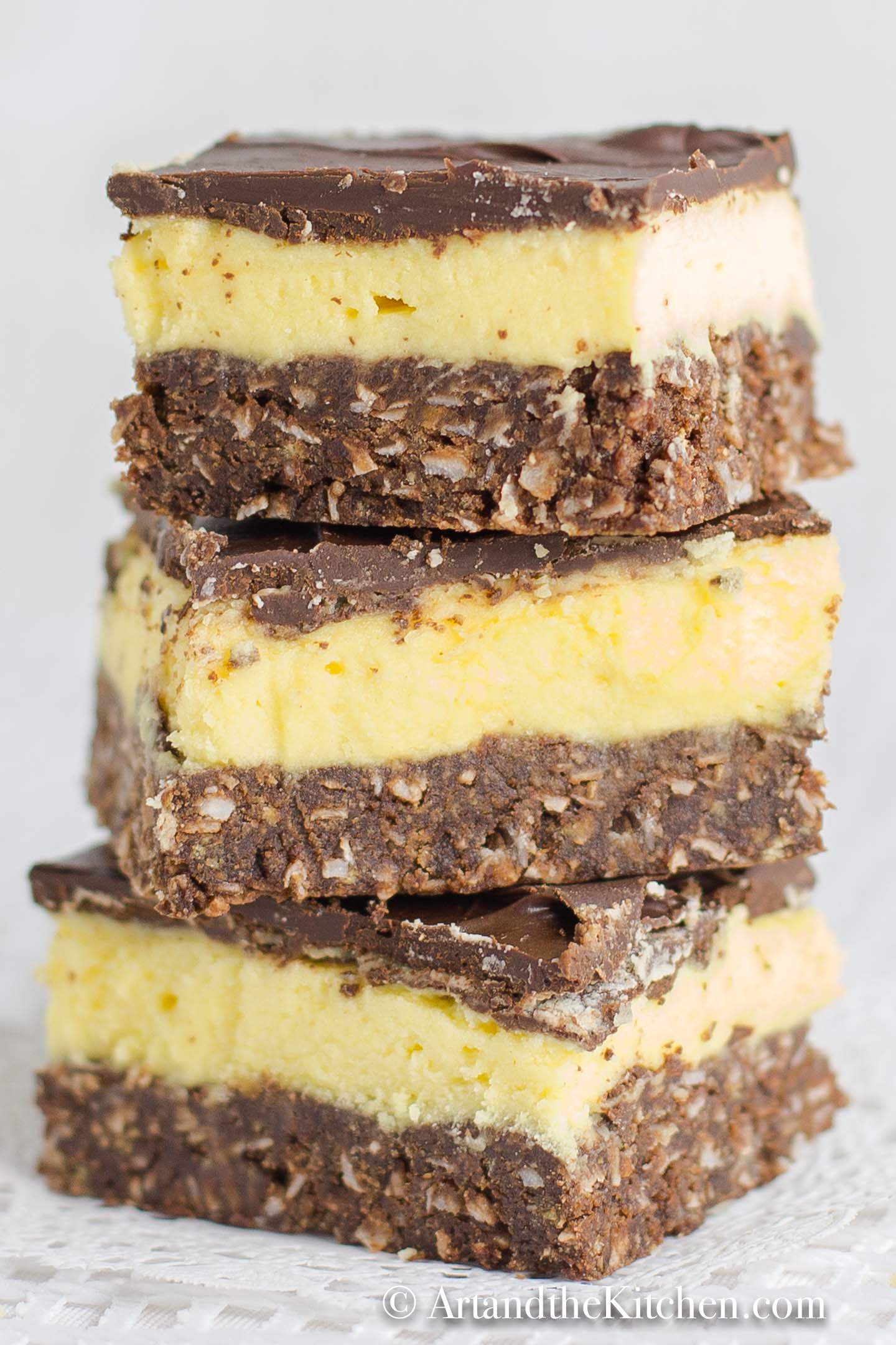 Stack of squares that have layers of chocolate, yellow custard and chocolate coconut crust.