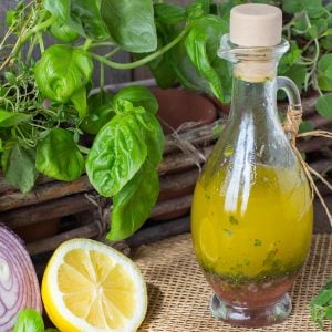 Decorative container of herb dressing and planter of fresh herbs, red onion, and sliced lemon.