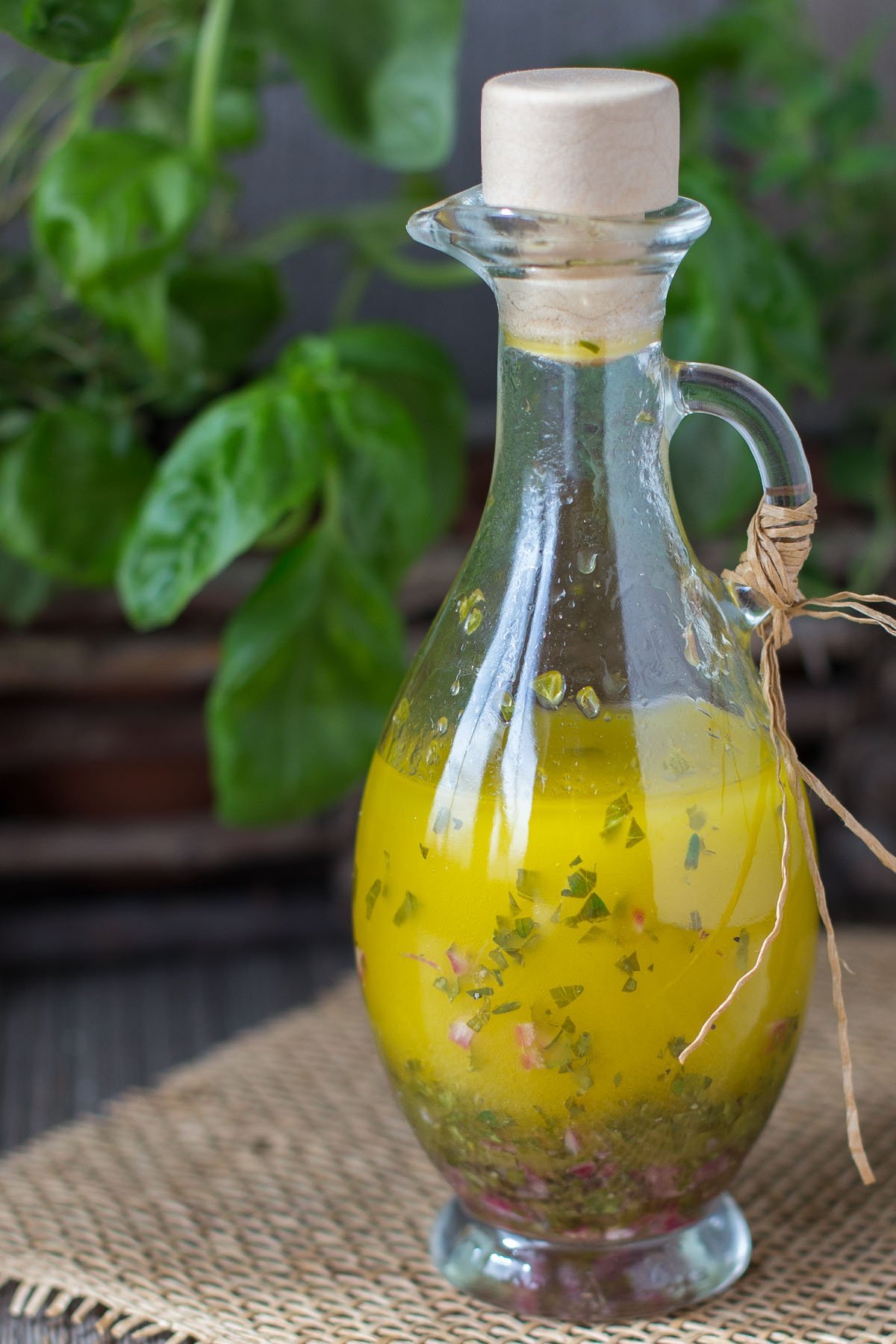 Decorative container of herb dressing and planter of fresh herbs, red onion, and sliced lemon.