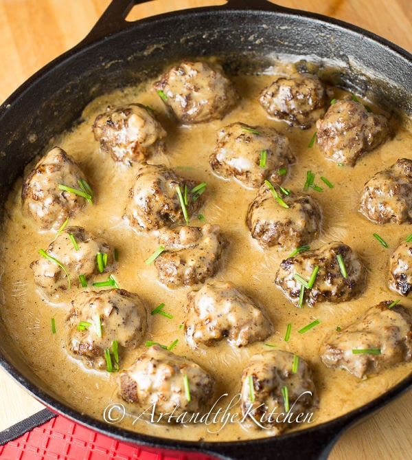 Meatballs cooked in a creamy gravy sauce in cast iron skillet.