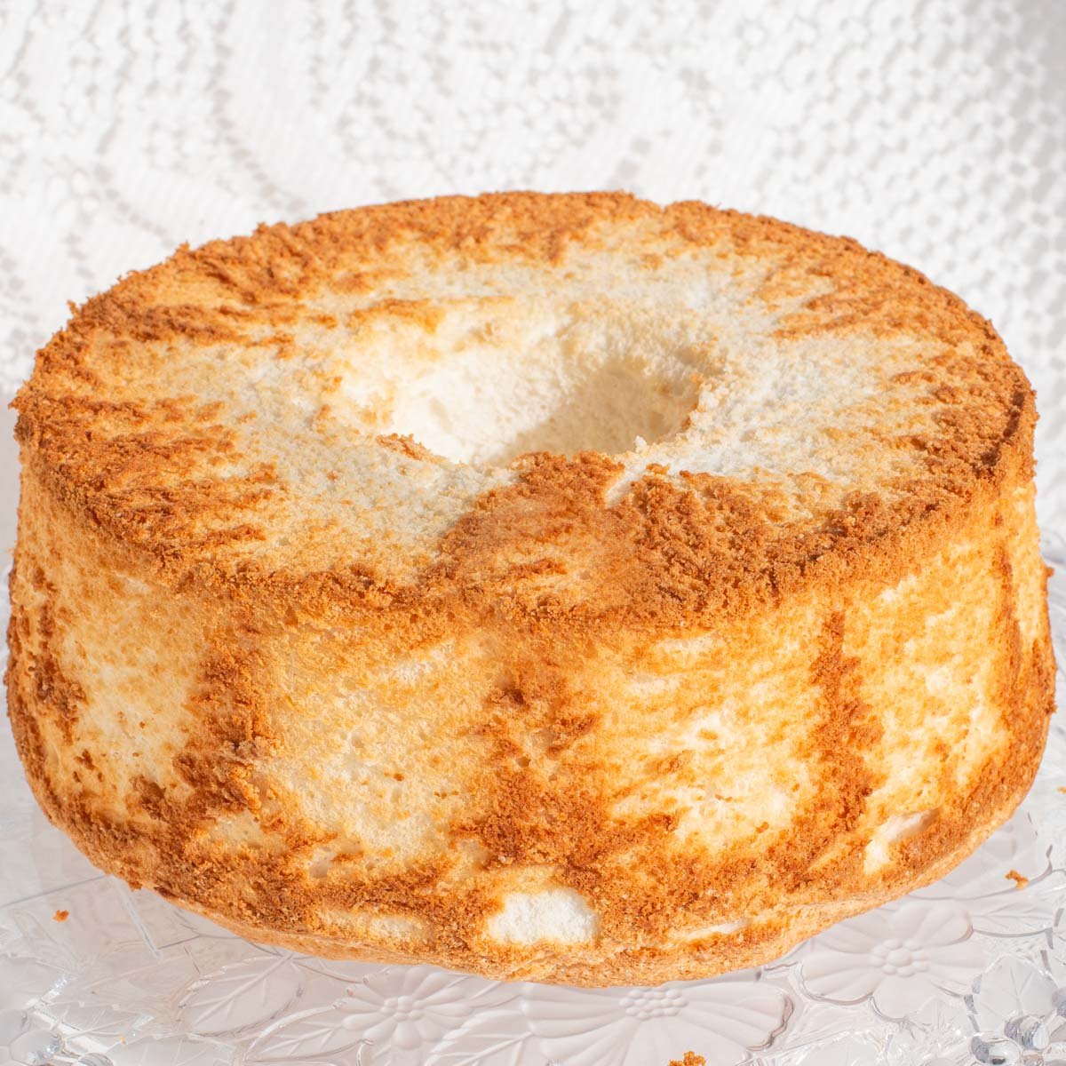 Whole angel food cake on glass plate.