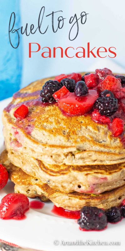 Stack of whole wheat pancakes topped with berries on a white plate.