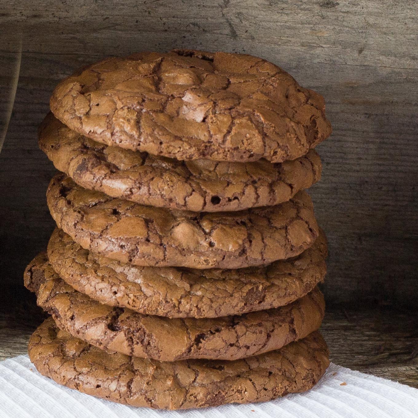 Stack of chocolate cookies on white cloth.