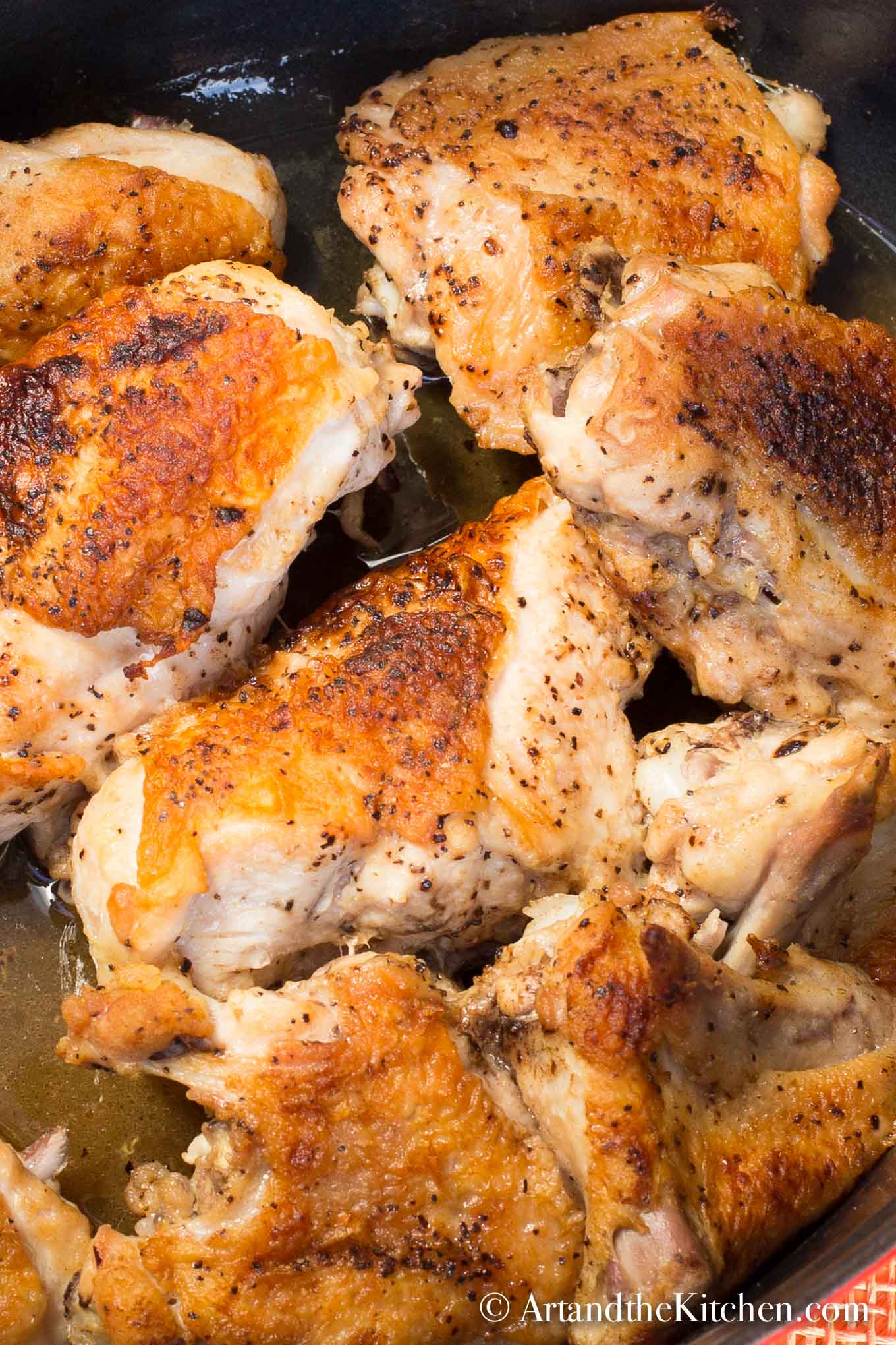 Cut up pieces of chicken roasted in large black roasting pan.
