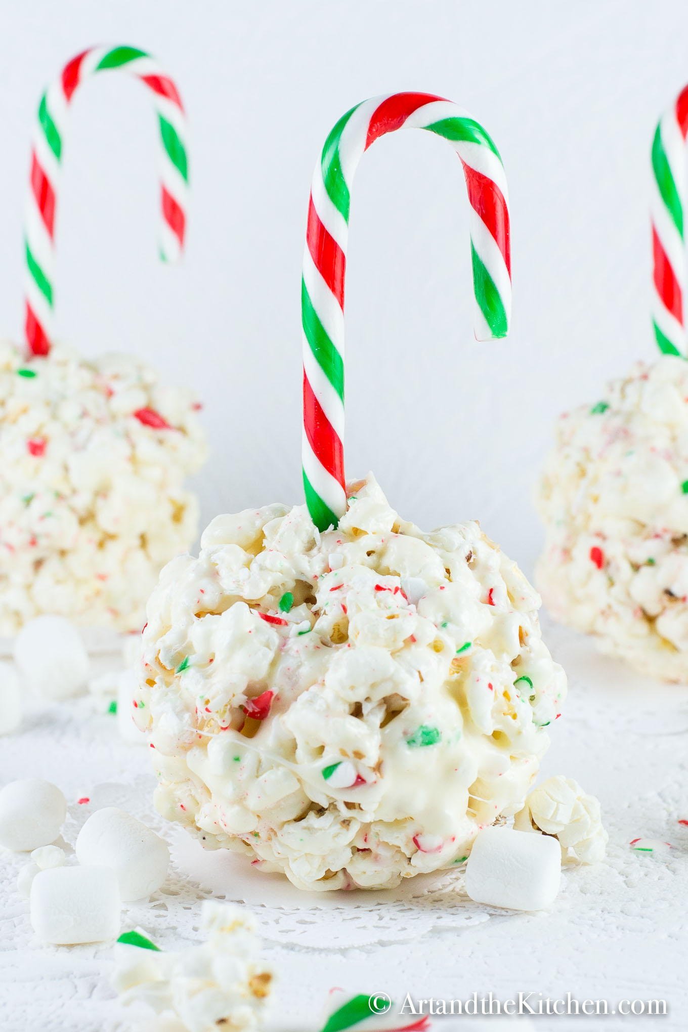 Popcorns ball made with crushed candy canes and a candy cane stick. 