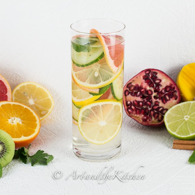 Tall glass of water with cucumber, grapefruit and lemon slices.