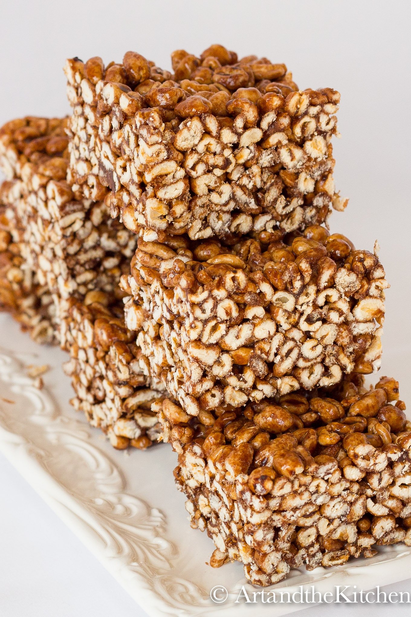 Stack of squares made of puffed wheat on white plate.
