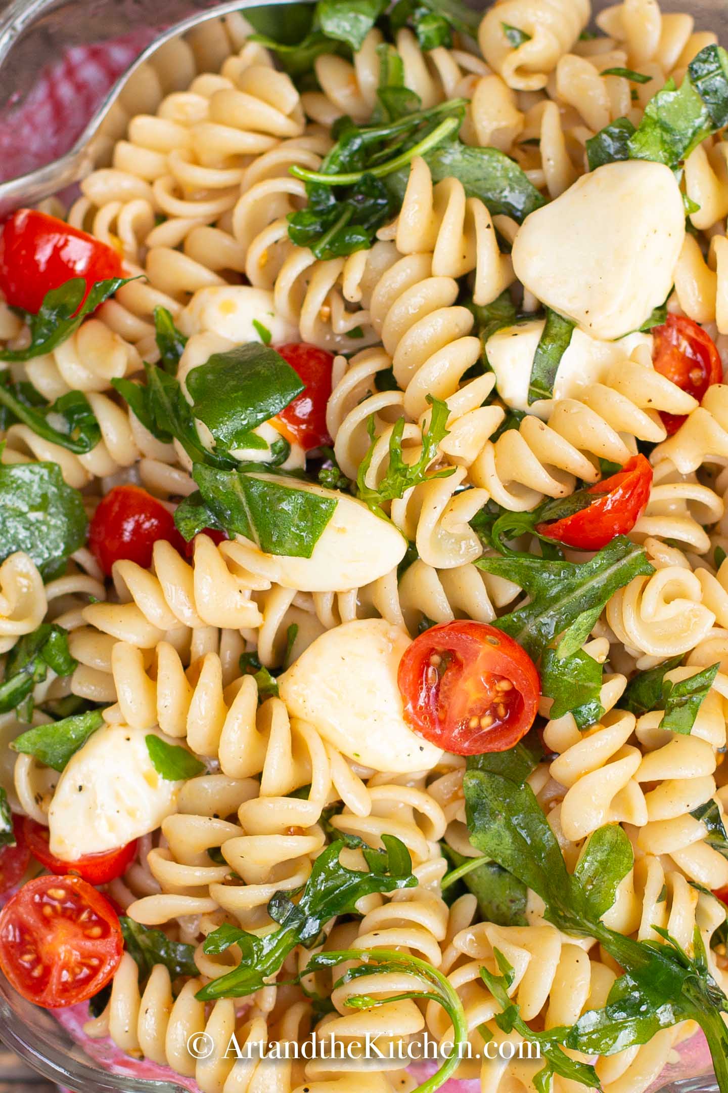 Rotini pasta tossed together with bocconcini, garden fresh cherry tomatoes, arugula, and fresh basil.