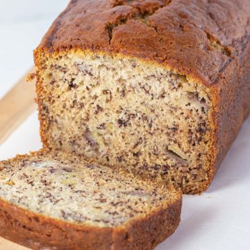 Whole loaf of banana bread with one slice cut.