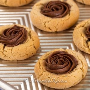 A baking sheet filled with peanut butter cookies topped with a dollop of whipped chocolate.