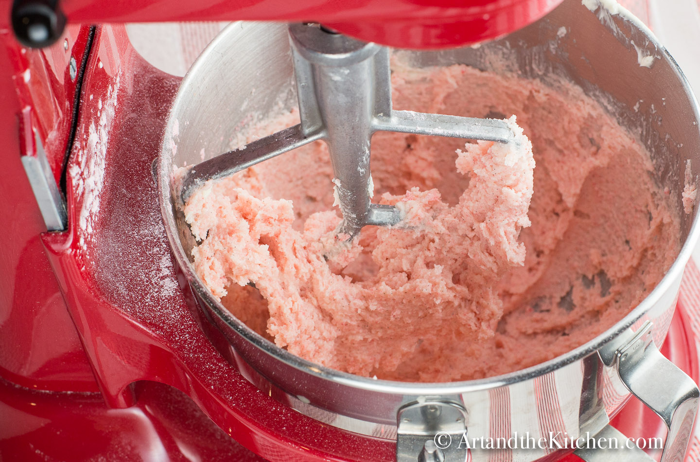 Electric mixer beating pink sugar cookie dough.