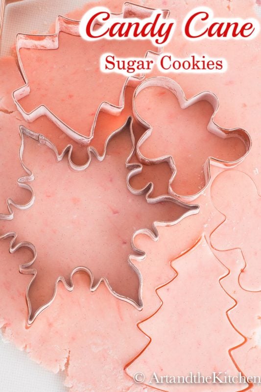 Pink sugar cookie dough rolled out with cookie cutters on top.