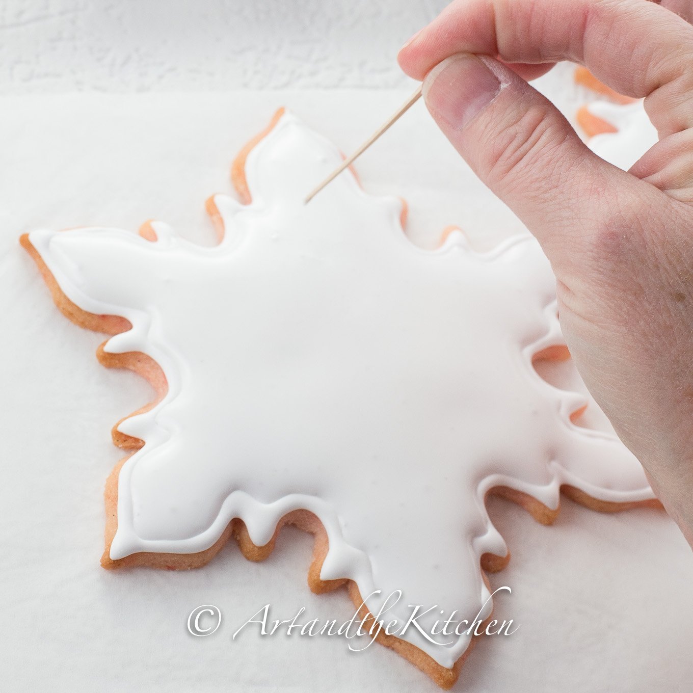Snowflake shaped cookie coated in white royal icing.