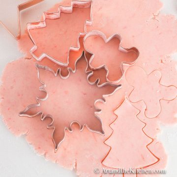 Rolled out pink sugar cookie dough with cookie cutters.