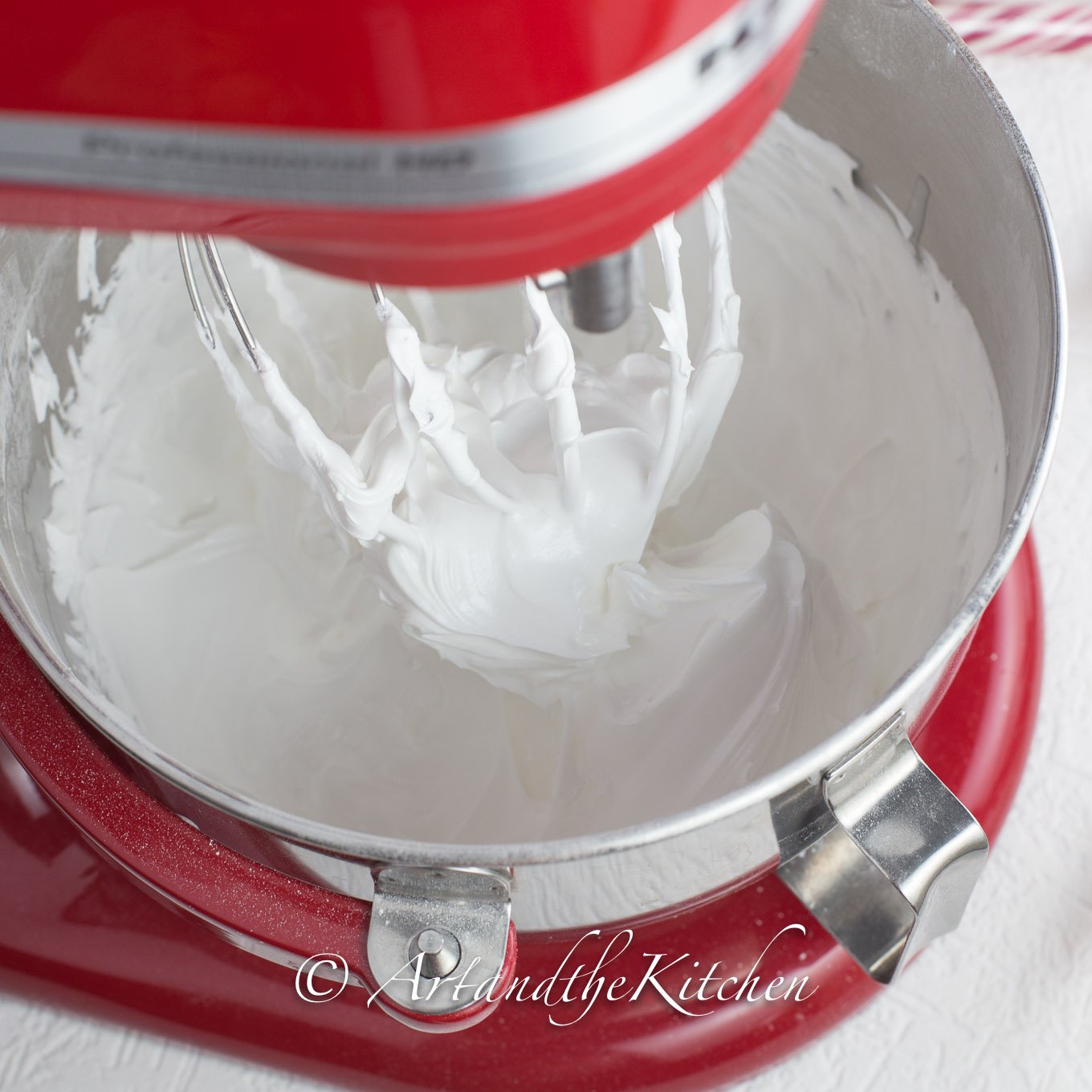 Red standing mixer with bowl filled with royal icing.