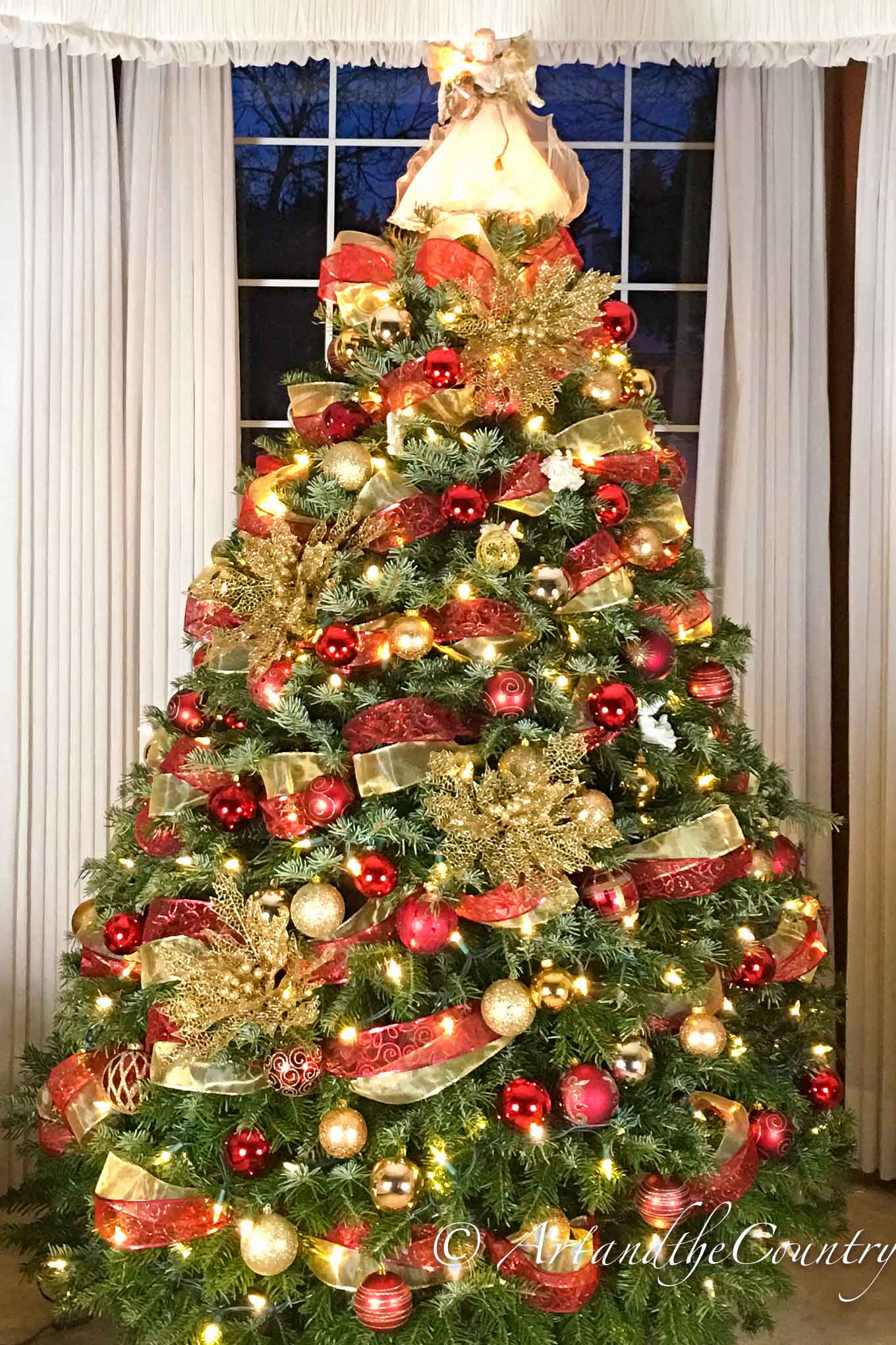 Christmas tree decorated with red and gold trim. Angel tree topper.