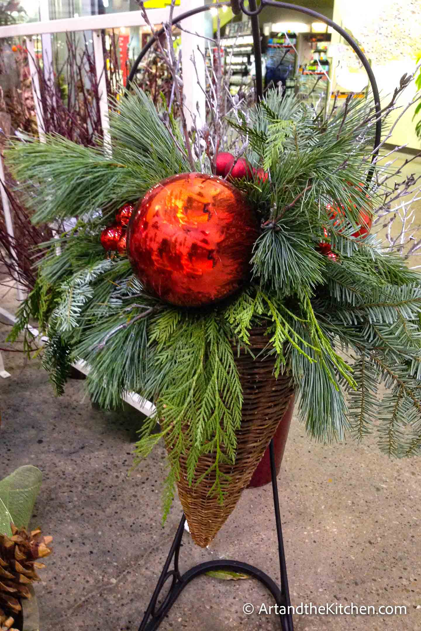 Outdoor Christmas planter with greenery, tree branches and decorations.