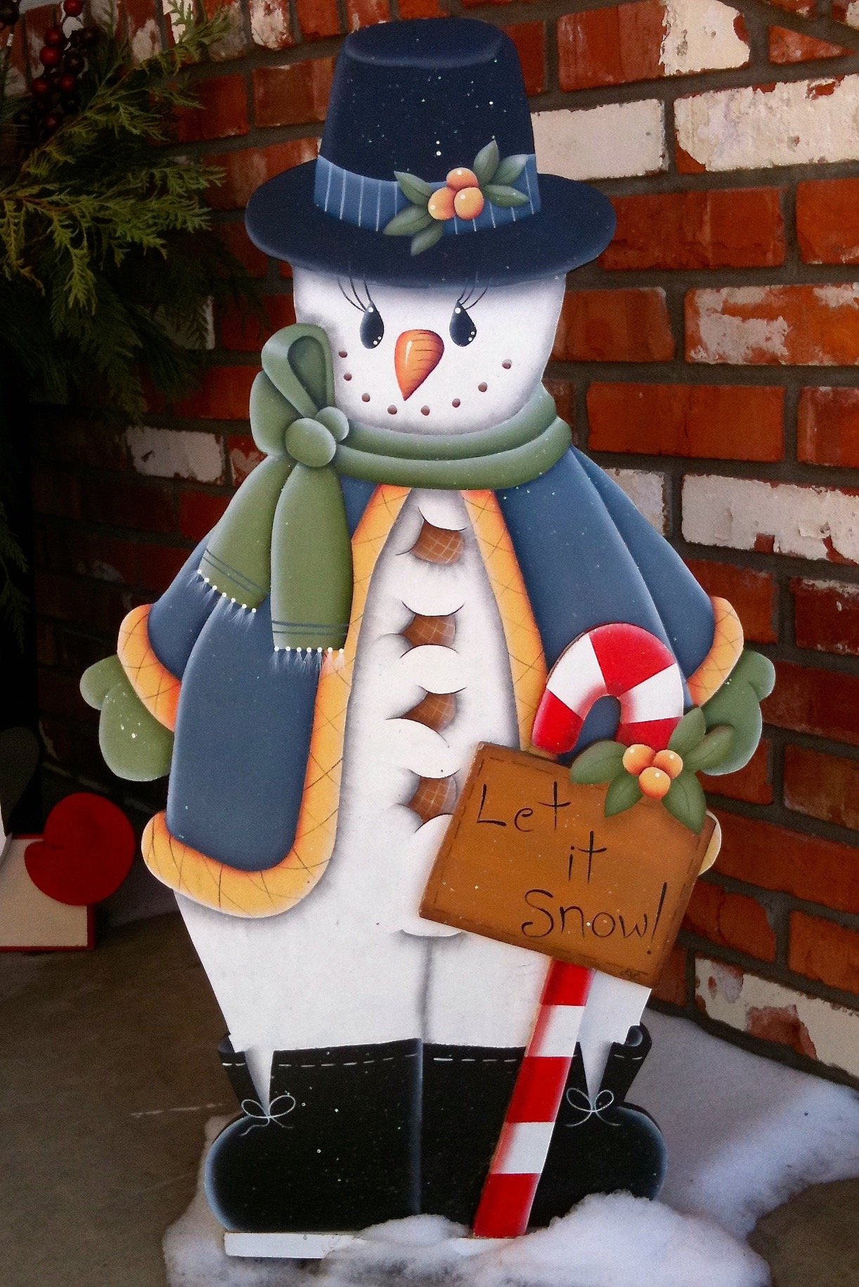 Decorative, hand-painted wood snowman on doorstep.