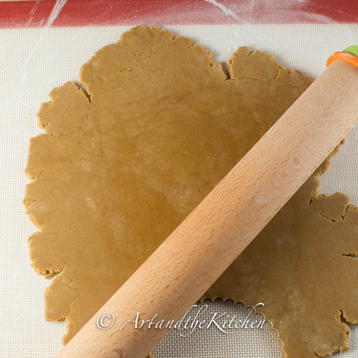 Wood rolling pin rolling out gingerbread dough.