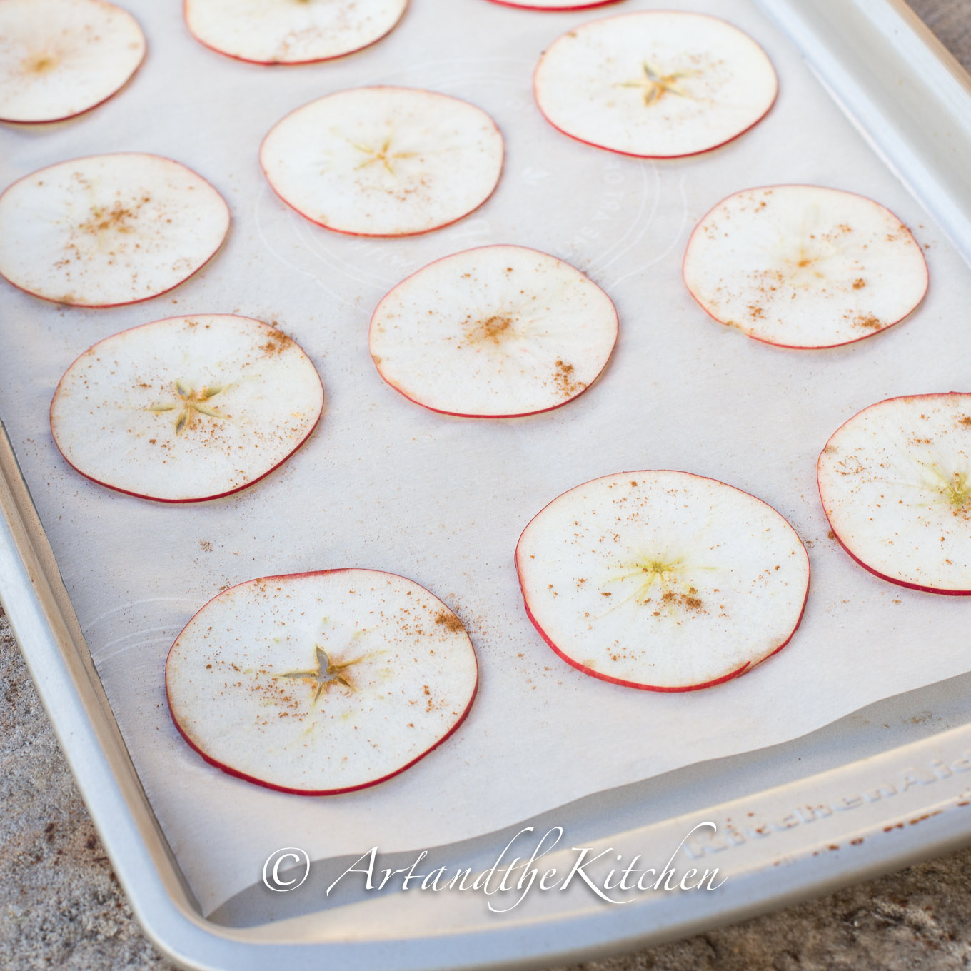 Apple slices on parchment lined baking sheet.