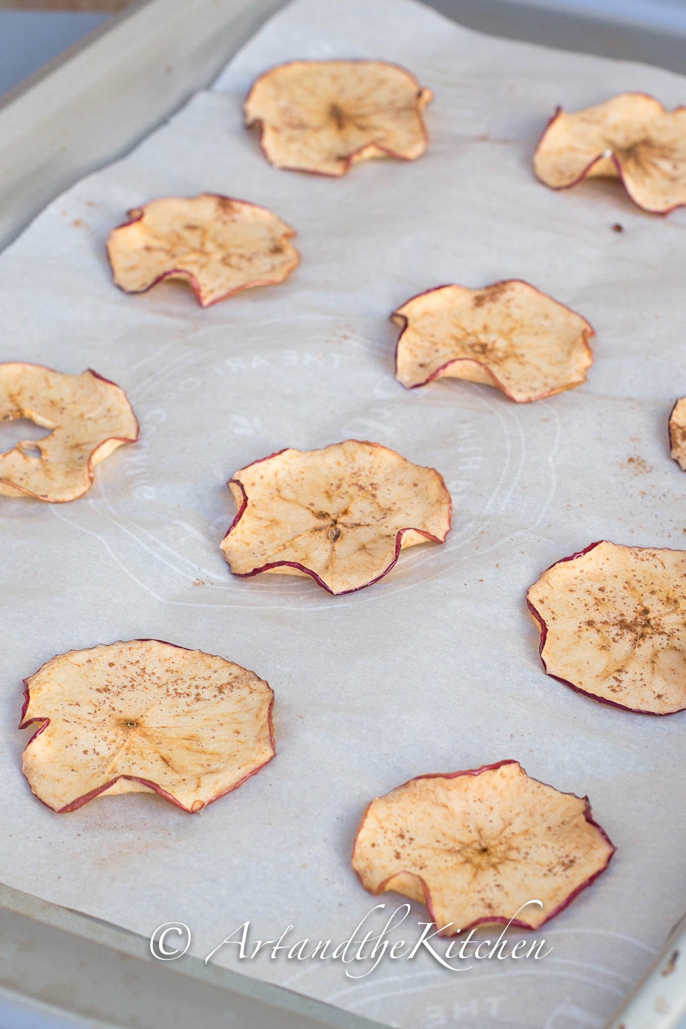 Apple Chips on parchment lined baking pan.