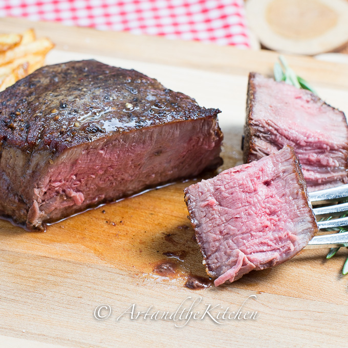 Sliced steak on wood cutting board.