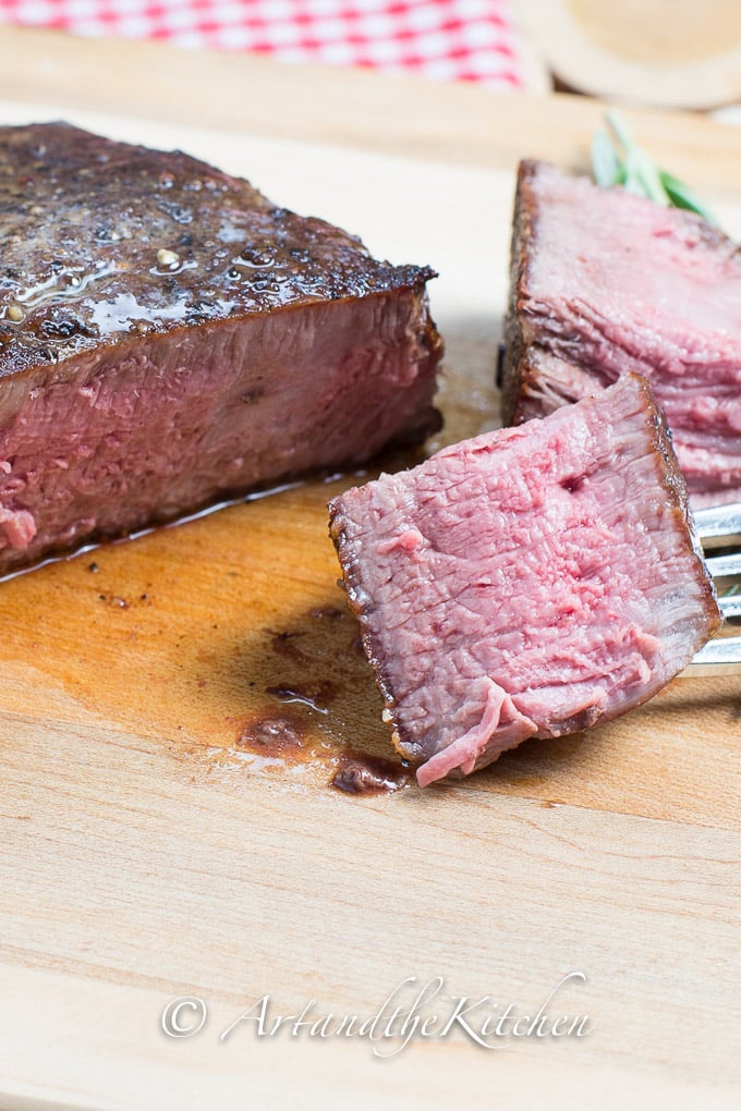 Sliced steak on wood cutting board.