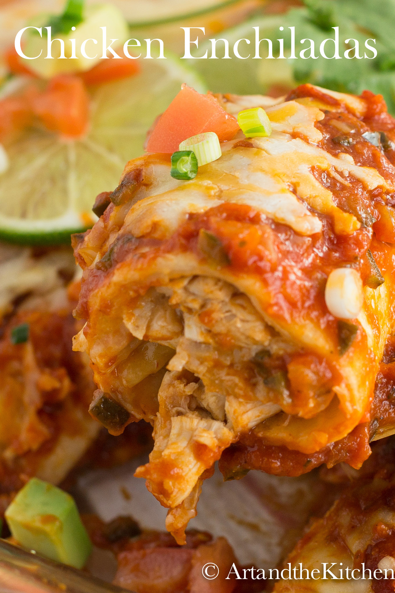 Baking dish of chicken Enchiladas topped with melted cheese, lime slices and chucks of avocado, tomatoes and green onions.