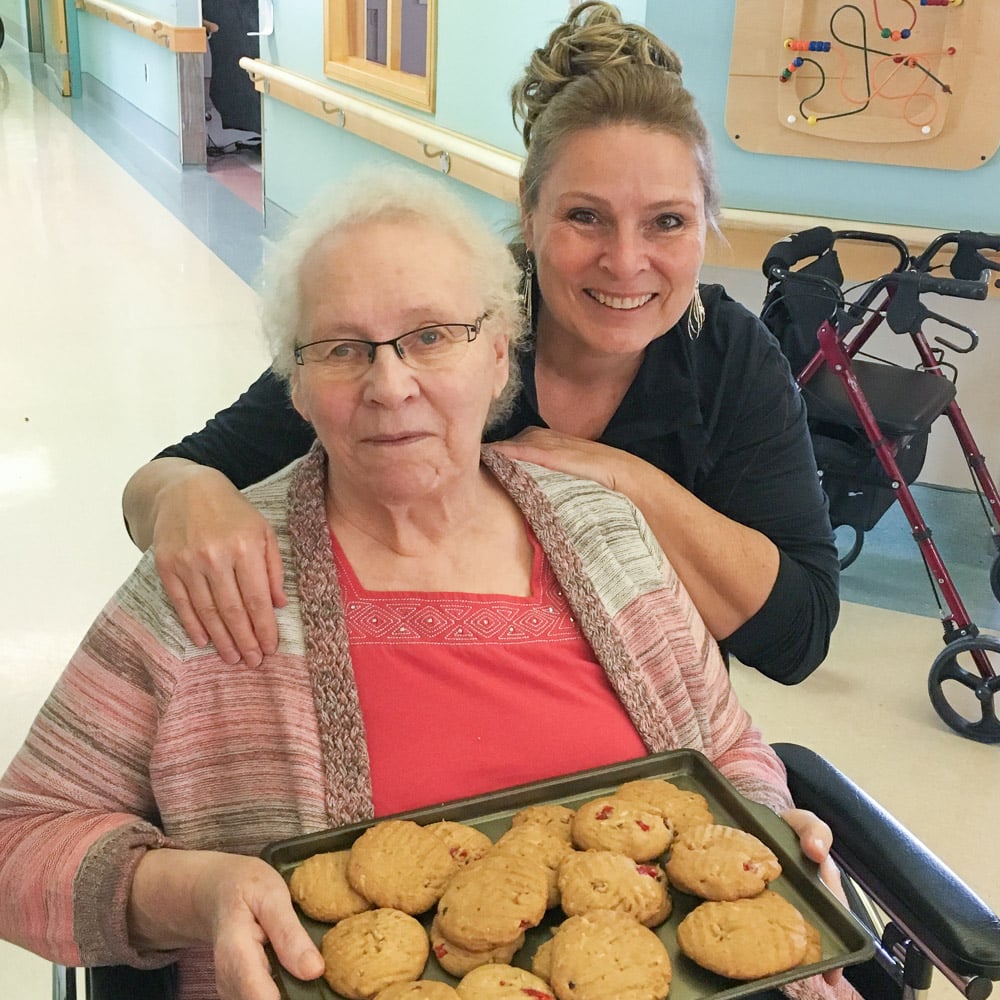 Elderly mom and daughter with tray of baked cookies.