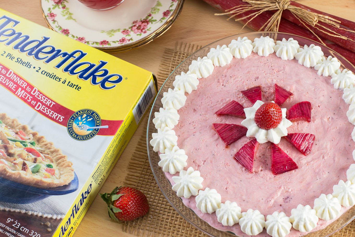 Mousse pie with strawberries and rhubarb, decorated with whipped cream dollops.