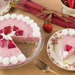 Mousse pie with strawberries and rhubarb, decorated with whipped cream dollops.