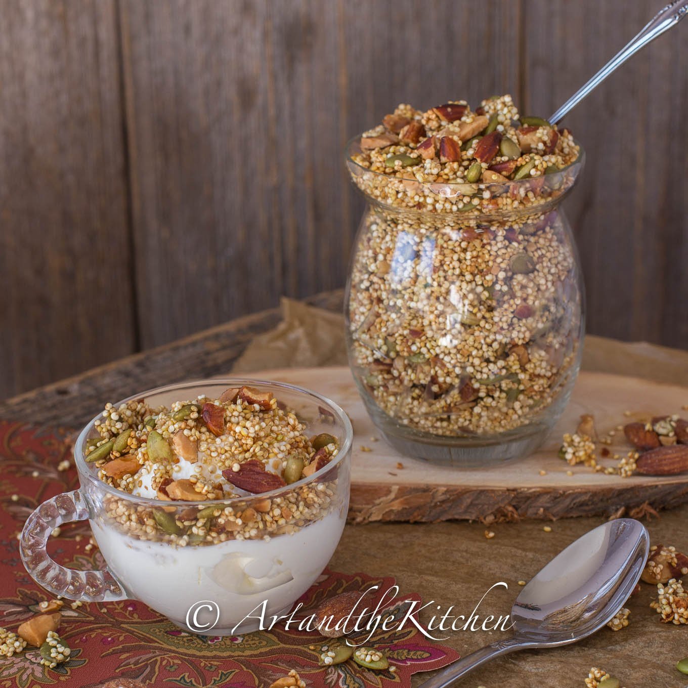 Glass bowl of yogurt topped with quinoa granola and jar full of granola.