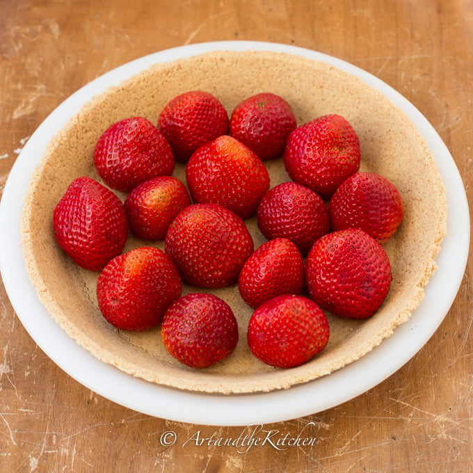White pie plate filled with graham crust and fresh whole strawberries.