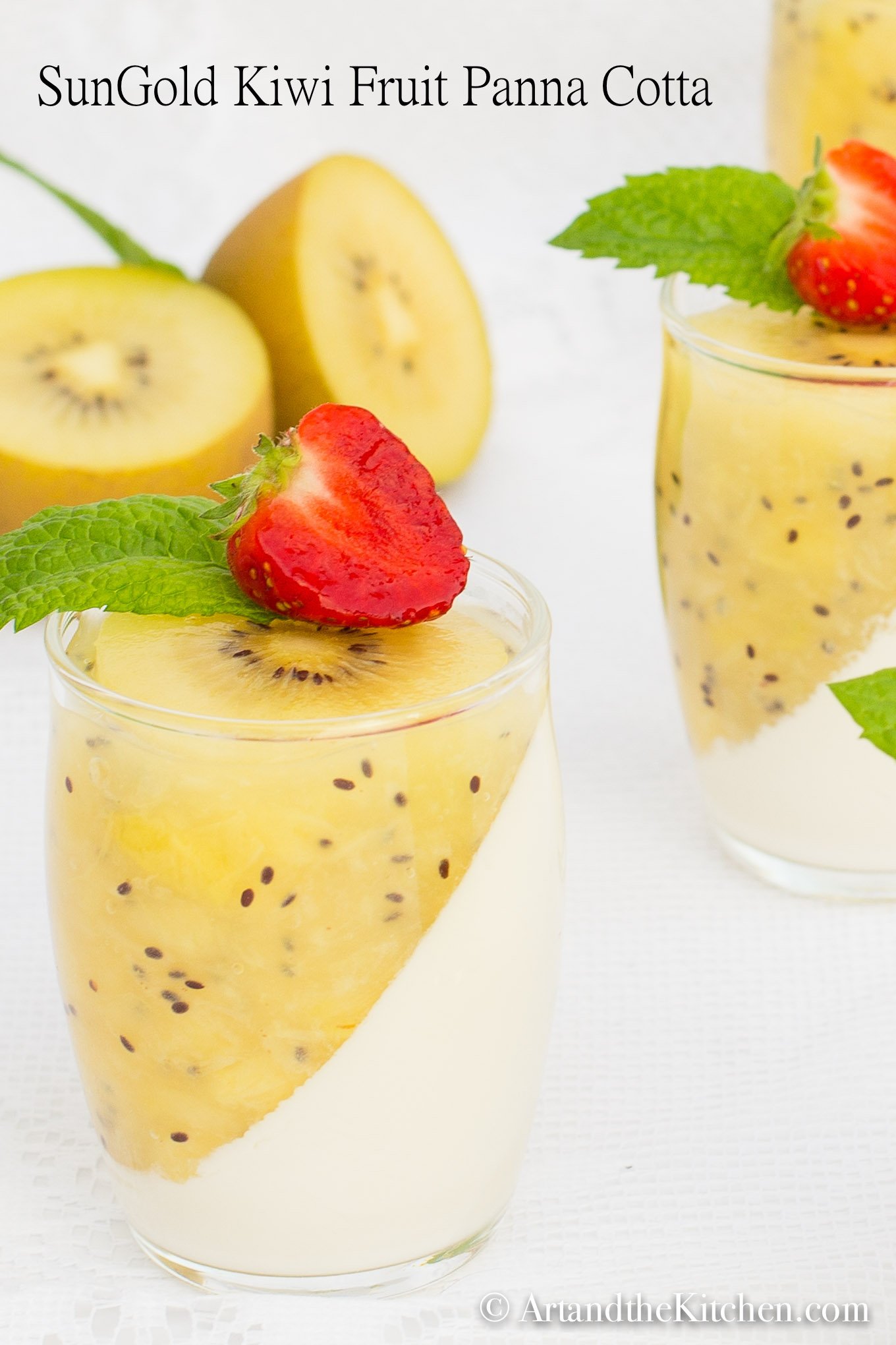 Glass jars filled with panna cotta and kiwi puree topped with mint and strawberry slice.