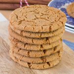 A stack of homemade ginger cookies on a wooden board.