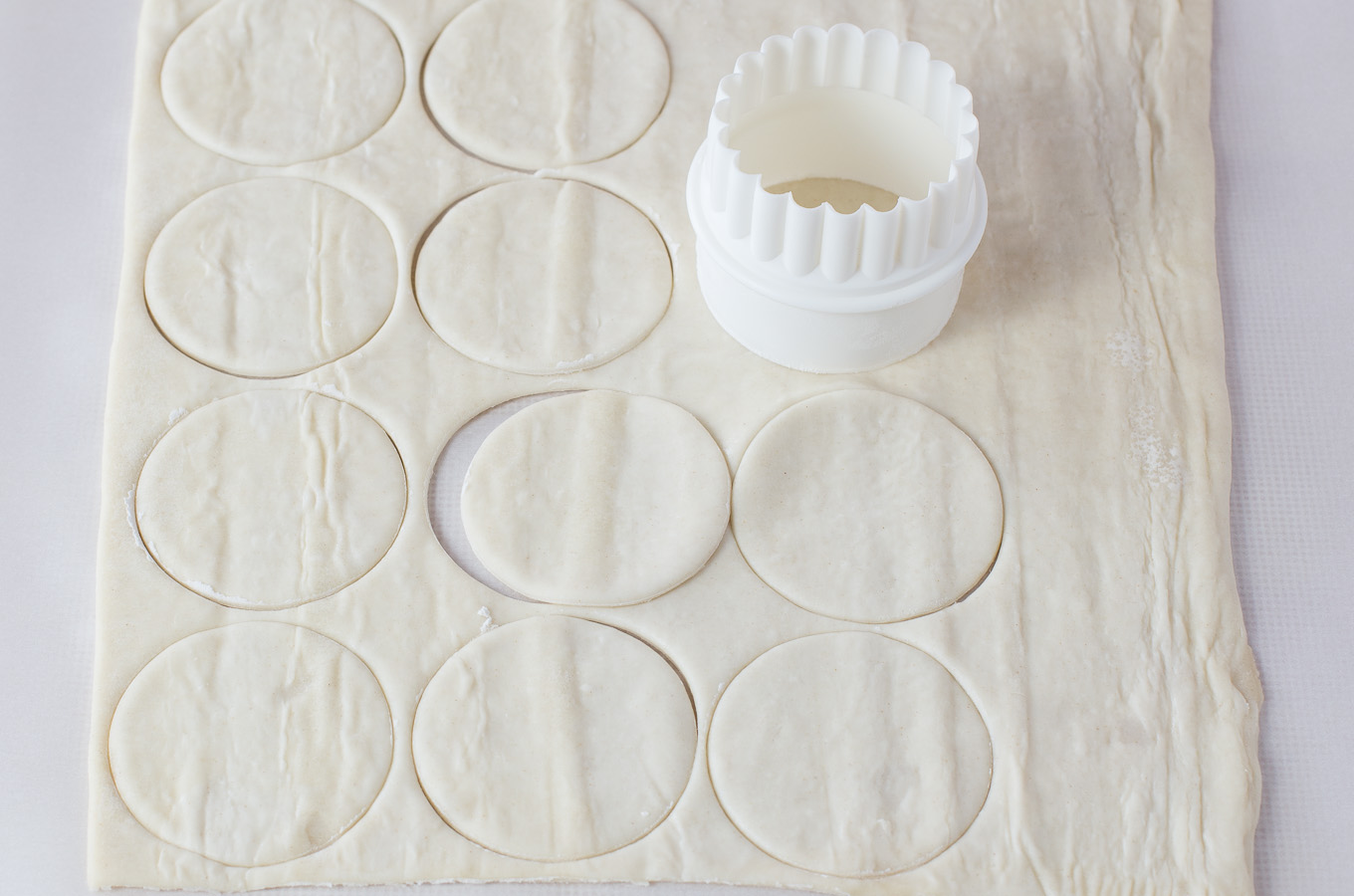 Sheet of puffed pastry cut out with circle cookie cutter.