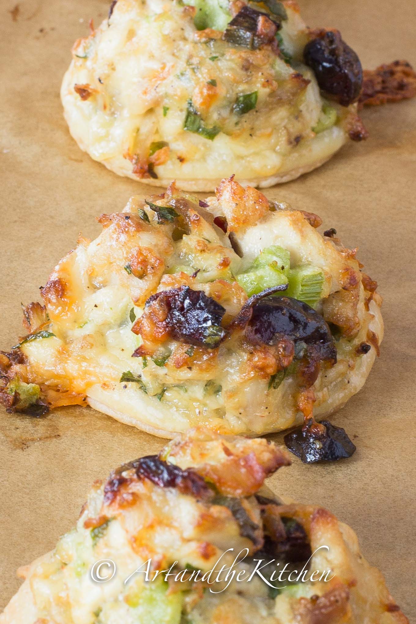 Bites of puffed pastry topped with turkey salad mix and cranberries.